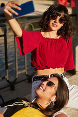 Wall Mural - Two teenager girls sitting taking a selfie.