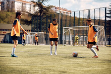 Young Women Practicing With Ball During Soccer Training On Playing Field.