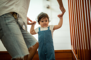 Wall Mural - cute toddler little child family concept, baby learning to walk with father and mother to help care and holding hand, first step with childhood parent support, small love portrait little boy at home