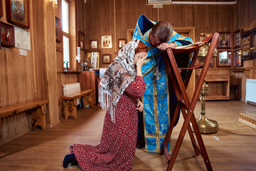 Wall Mural - a woman repents of her sins, confessions with a priest in an Orthodox church