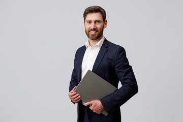 Portrait of successful businessman with beard holding laptop. Studio shoot