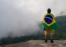 Young Man At Mountain Looking To Horizon In Nature With Brazilian Flag.