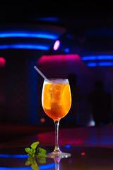 aperol syringe in glass with orange, summer cocktail with tubules, over black background.