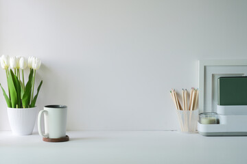 Wall Mural - Comfortable workplace with picture frame, coffee, stationery and houseplant on white table.