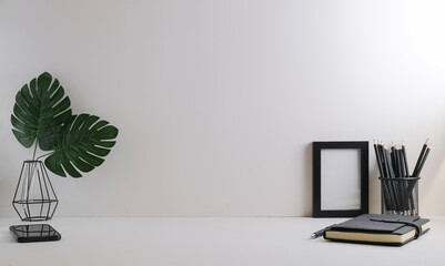 Wall Mural - Home office desk with, stationery, picture frame and potted plant on white table. Copy space.