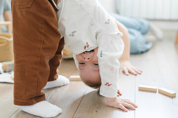 Wall Mural - Children play on the floor of the children's room. Little brother amuses his brother and sister stands on his head at home. Family lifestyle concept