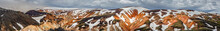 Panoramic Amazing Icelandic Landscape Of Colorful Rainbow Volcanic Landmannalaugar Mountains, At Famous Laugavegur Hiking Trail With Dramatic Snowy Sky, And Red Volcano Soil In Iceland