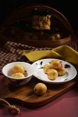 homemade peranakan nonya pineapple fruit tart with clove in cock plate and bottle on traditional kampong red background halal cookies menu for Chinese new year and Malay raya festival 