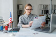 © AnnaStills - Modern Caucasian woman wearing eyeglasses working in visa service department looking through documents