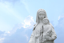 Beautiful Statue Of Virgin Mary And Baby Jesus With Rosary Beads Outdoors. Space For Text