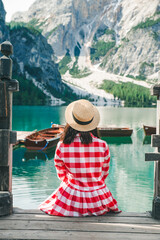 Wall Mural - woman in red sundress sitting on wooden stairs looking at lake in mountains