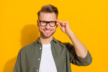 Wall Mural - Portrait of attractive cheerful content intellectual guy touching specs isolated over vibrant yellow color background