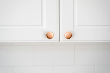 Wall Mural - Two small round copper door knob on white kitchen cabinet