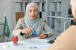 © AnnaStills - Young adult Muslim consular officer working in Saudi Arabia embassy giving approval for travel visa to Caucasian man