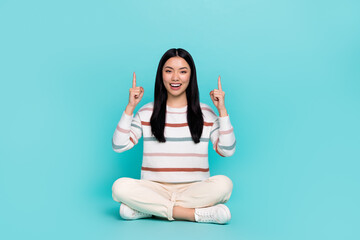 Poster - Photo of attractive good mood young girl sitting floor promote demonstrate product isolated on turquoise color background