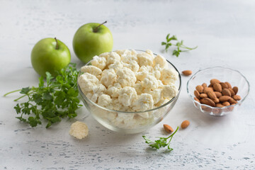 Wall Mural - Vegetable salad ingredients: cauliflower, apples, almonds, parsley  on light blue background. Cooking healthy homemade food