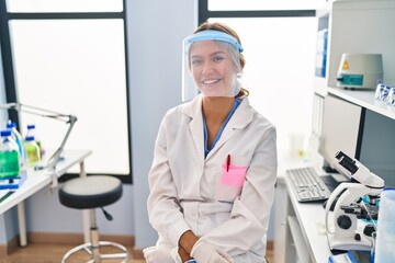 Canvas Print - Young blonde woman working at scientist laboratory wearing face mask with a happy and cool smile on face. lucky person.