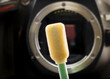 Foam tip cleaning swab in front of DSLR camera body 