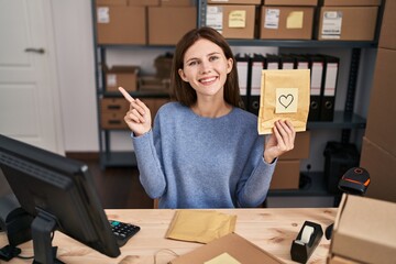 Poster - Young brunette woman working at small business ecommerce smiling happy pointing with hand and finger to the side