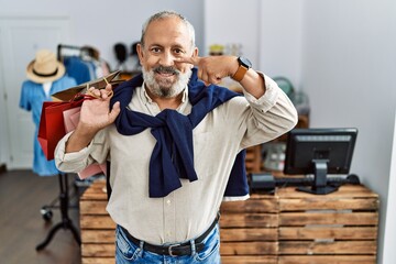 Canvas Print - Handsome senior man holding shopping bags at boutique shop pointing with hand finger to face and nose, smiling cheerful. beauty concept