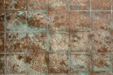 Background Of Copper And Bronze Square Tiles With Oxidations, Dust And Stains. The Texture Of The Copper Background Is Covered With A Patina, Can Be Used As Backdrop.
