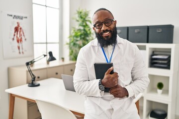 Sticker - Young african american man wearing doctor uniform holding book at clinic