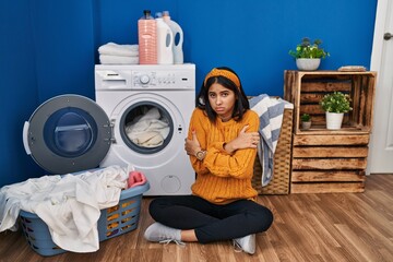 Poster - Young hispanic woman doing laundry shaking and freezing for winter cold with sad and shock expression on face