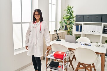 Canvas Print - Young hispanic woman wearing doctor uniform and stethoscope looking positive and happy standing and smiling with a confident smile showing teeth