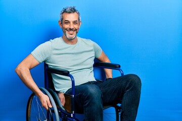 Canvas Print - Handsome middle age man with grey hair sitting on wheelchair with a happy and cool smile on face. lucky person.