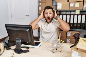 Canvas Print - Handsome hispanic man working at small business commerce crazy and scared with hands on head, afraid and surprised of shock with open mouth