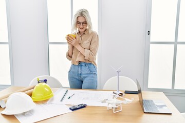 Poster - Young caucasian woman drinking coffee working at architect studio