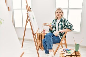 Poster - Young artist woman painting on canvas at art studio depressed and worry for distress, crying angry and afraid. sad expression.