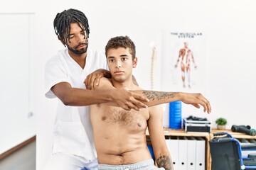 Wall Mural - Two men physiptherapist and patient having rehab session stretching arm at clinic