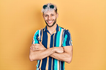 Wall Mural - Young hispanic man with modern dyed hair wearing summer shirt and sunglasses happy face smiling with crossed arms looking at the camera. positive person.