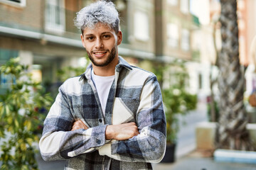 Wall Mural - Young hispanic man smiling happy with arms crossed gesture at the city.