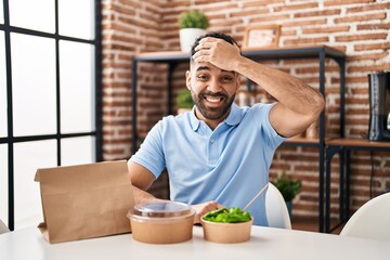 Canvas Print - Hispanic man with beard eating delivery salad stressed and frustrated with hand on head, surprised and angry face