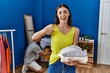 © Krakenimages.com - Young brunette woman holding folded laundry pointing finger to one self smiling happy and proud