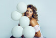 Beautiful young woman in a romantic dress with white balloons.