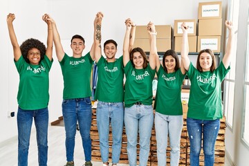 Wall Mural - Group of young volunteers smiing happy with hands raised up at charity center.