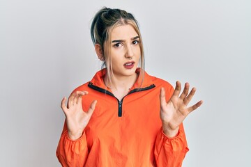 Wall Mural - Young modern girl wearing sports sweatshirt disgusted expression, displeased and fearful doing disgust face because aversion reaction. with hands raised