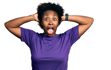 Sticker - African american woman with afro hair wearing casual purple t shirt crazy and scared with hands on head, afraid and surprised of shock with open mouth