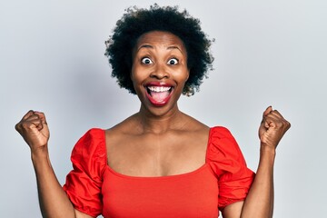 Canvas Print - Young african american woman wearing casual clothes celebrating surprised and amazed for success with arms raised and open eyes. winner concept.