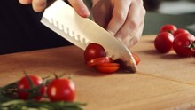 Woman Cutting Cherry Tomatoes For Salad. Female Hands Cut Cherry Tomatoes On Wood Board Slow Motion.