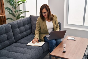 Wall Mural - Middle age woman psychologist using laptop reading book at psychology center