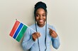 African american woman with braided hair holding gambia flag smiling happy pointing with hand and finger