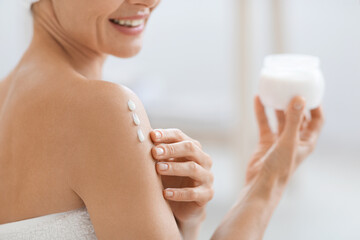 Wall Mural - Cropped of adult lady using body lotion after shower