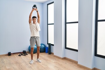 Canvas Print - Young hispanic man smiling confident training using kettlebell at sport center