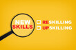 New skills written on yellow paper with magnifying glass. Development concept and reskilling and up skilling idea