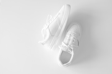 White women's leather sneakers on white background top view flat lay. Stylish youth sneakers, sports shoes, genuine leather footwear. Minimalistic shoe store advertising fashion style Shoe background