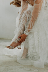 Bride dresses shoes before the wedding ceremony. bride morning. Closeup detail of bride putting on high heeled sandal wedding shoes.